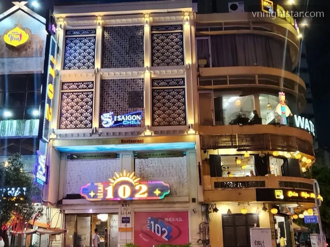 밤에 불이 켜진 건물 1층 입구 위에 102 숫자 조명이 걸린 모습
