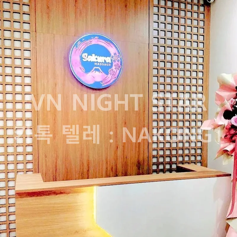 푸꾸옥 사쿠라 마사지 접수대 — 목재 격자 벽의 Sakura Massage 원형 로고