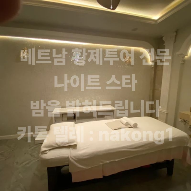 간접 조명이 들어온 베이지 톤 관리실의 마사지 베드와 개어 둔 수건