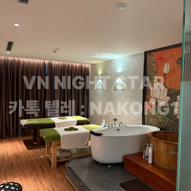 연꽃 벽화 앞에 관리 베드 두 대와 흰 욕조가 놓인 룸